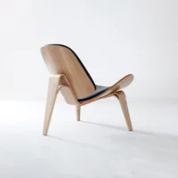 A modern wooden lounge chair with curved legs and a black cushioned seat and backrest, set against a plain white background.