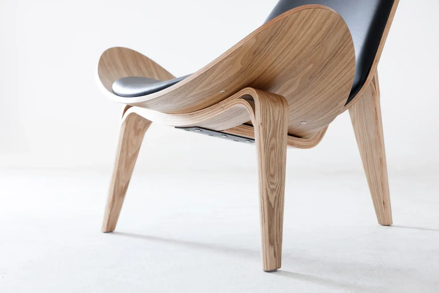 Detail display1 A modern chair with curved wooden legs and frame, featuring a black cushioned seat and backrest, set against a plain white background.