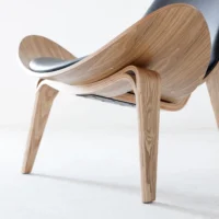 A modern chair with curved wooden legs and frame, featuring a black cushioned seat and backrest, set against a plain white background.