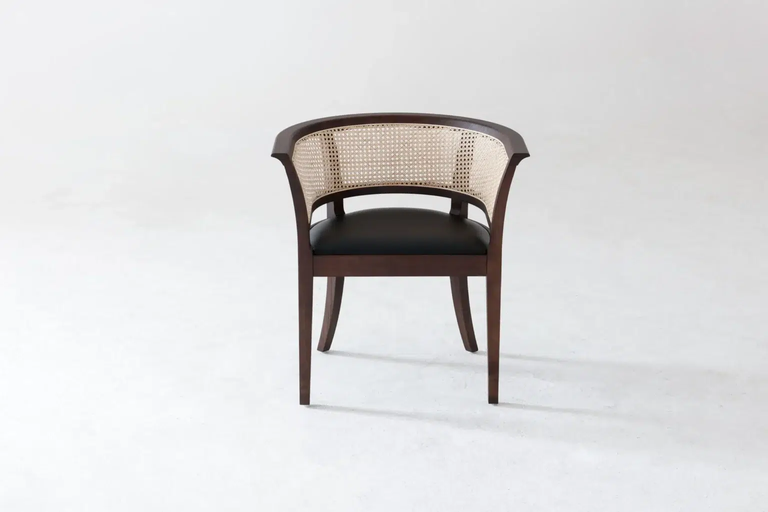Front view A dark wooden chair with a curved backrest and cane webbing, featuring a black cushioned seat, is positioned on a light, plain background.