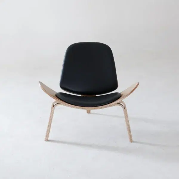 A modern black lounge chair with wooden legs and a curved seat, photographed against a plain light grey background.