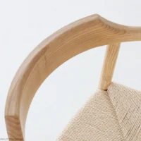 A close-up, angled view of a wooden chair with a curved, smooth backrest and a woven, natural fibre seat against a plain white background.