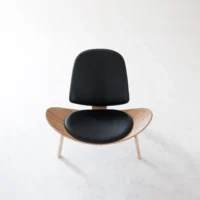 A modern chair with a curved wooden seat, light wooden legs, and black cushioned backrest and seat, photographed from above on a plain white background.