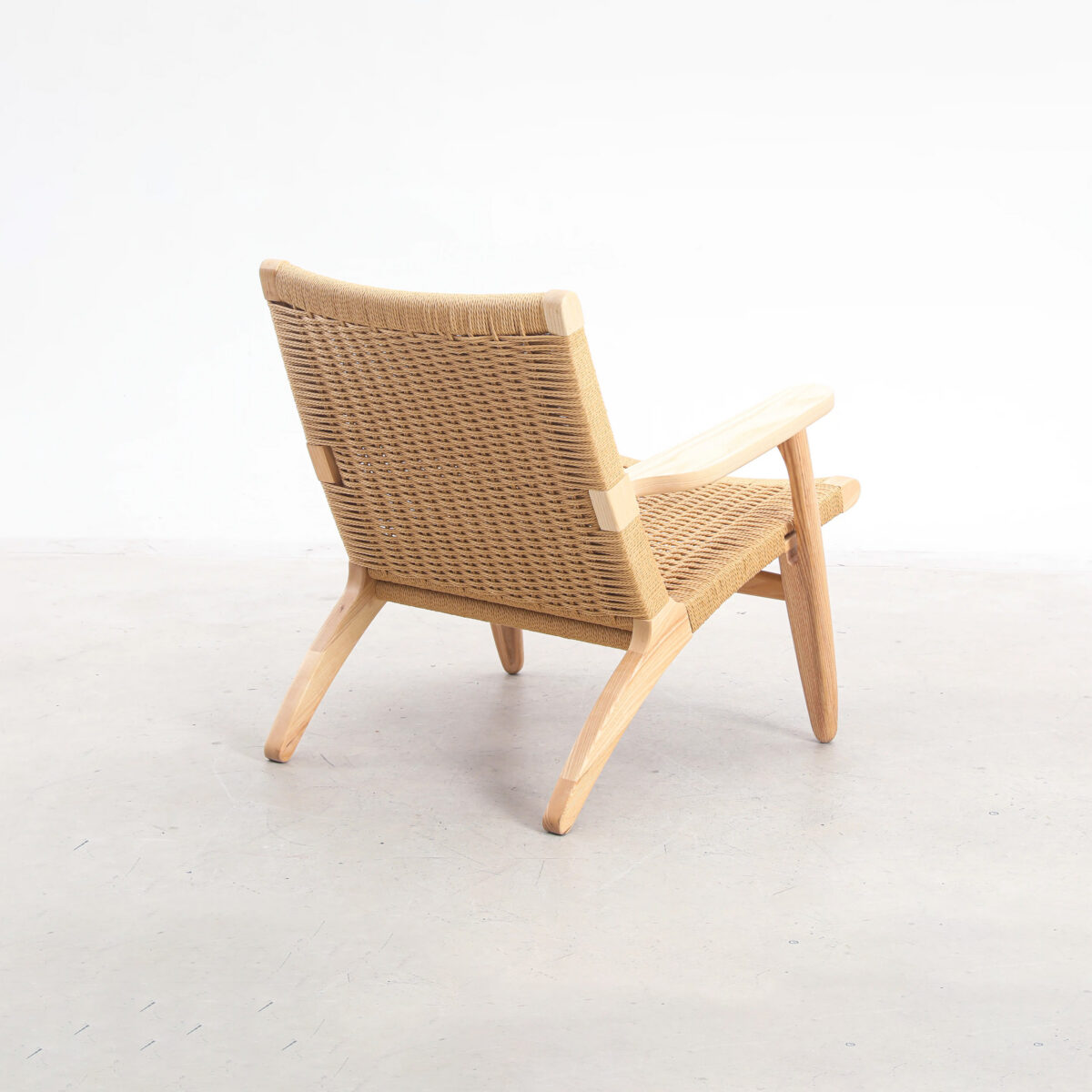 Easy Chair_B1 A mid-century modern lounge chair with a woven rattan back and seat, and light wooden frame and legs, positioned on a light-coloured floor against a plain white background.