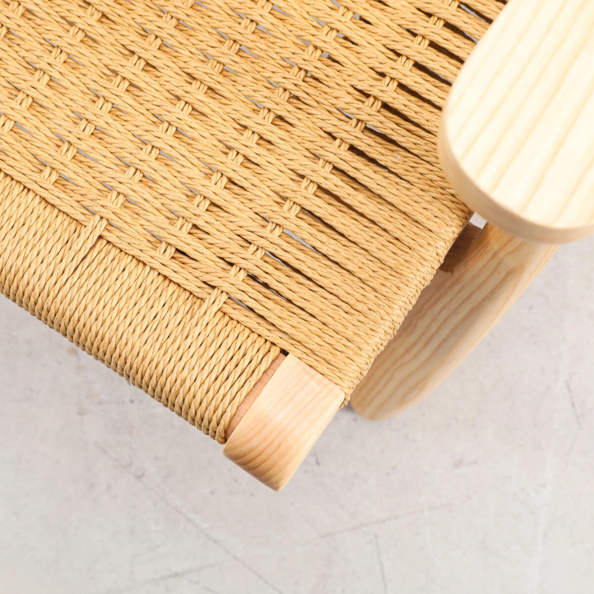 Easy Chair_B3 Close-up of a woven seat made of natural fibre or rope on a light wooden chair, shown from an angle above on a pale, smooth floor.
