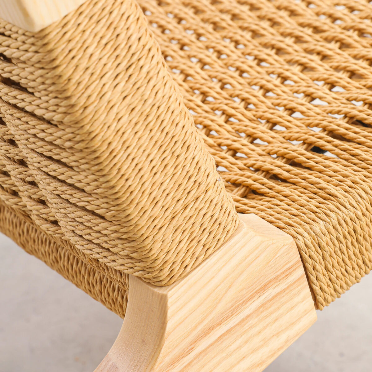 Easy Chair_B5 Close-up of a wooden chair with a tightly woven natural fibre seat and backrest, showcasing detailed craftsmanship and the light wood grain of the frame.