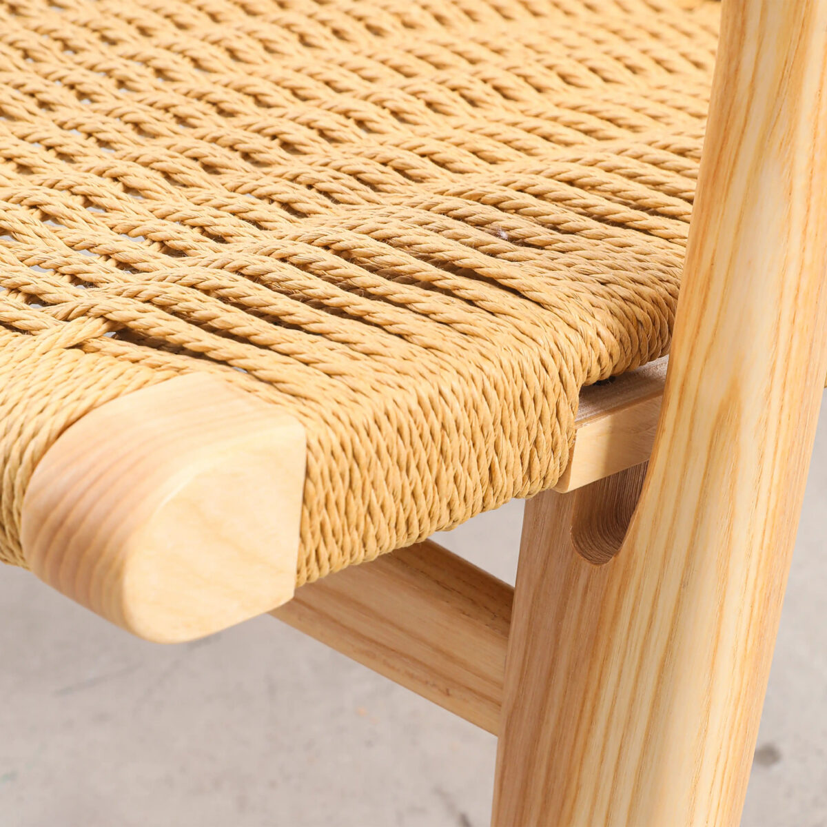 Easy Chair_B7 Close-up of a wooden chair with a woven natural fibre seat. The image highlights the detailed craftsmanship and texture of the woven seat and the smooth, light wood frame.