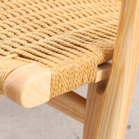 Close-up of a wooden chair with a woven natural fibre seat. The image highlights the detailed craftsmanship and texture of the woven seat and the smooth, light wood frame.