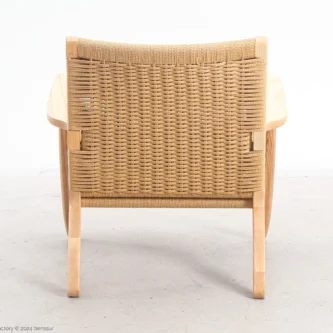 Back view of Hans Wegner's CH25 Easy Chair, highlighting the intricate woven paper rope backrest and the smooth wooden frame.