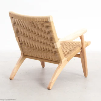 Back-side view of Hans Wegner's CH25 Easy Chair, showcasing the woven paper cord backrest and the sleek wooden frame.