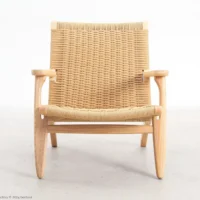 A wooden lounger with a light wood frame and woven rattan seat and backrest, photographed against a plain white background.