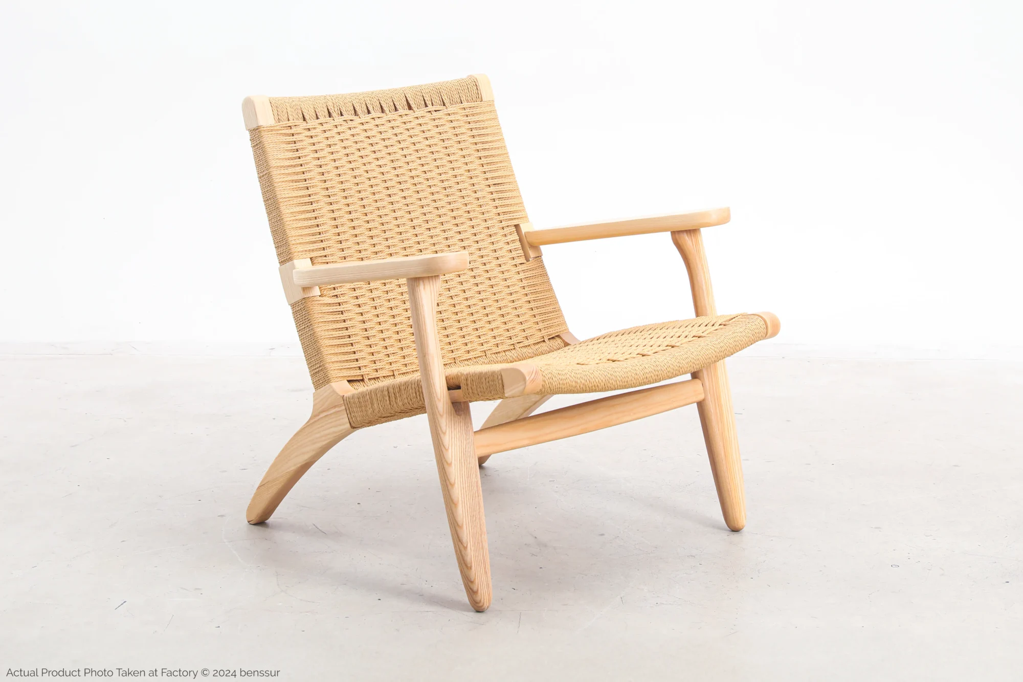 ront-side view of Hans Wegner's CH25 Easy Chair, showcasing its woven seat and backrest along with the solid wooden frame.