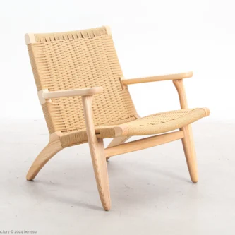 ront-side view of Hans Wegner's CH25 Easy Chair, showcasing its woven seat and backrest along with the solid wooden frame.