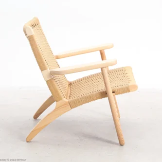 Side view of Hans Wegner's CH25 Easy Chair, showcasing its elegant wooden frame and woven paper cord seat and backrest.