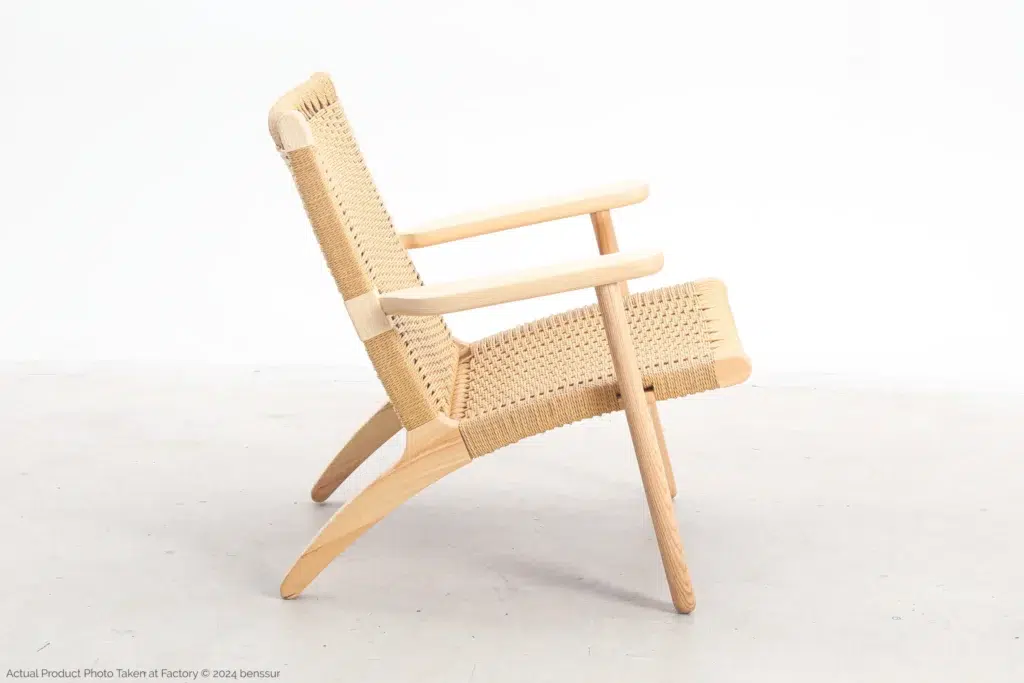 A modern lounge chair with a light wooden frame and woven cane seat and backrest, shown in side profile against a plain white background.
