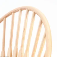Close-up of the upper half of a wooden chair backrest with vertical spindle slats, set against a plain white background.