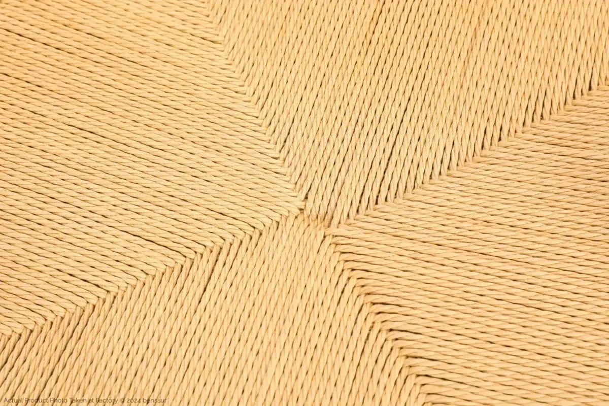Hans Wegner_Peacock Chair_Replica_Paper Rope_Natural_Ash_Detail_6 Close-up of a woven straw or wicker surface with a geometric, symmetrical pattern radiating from the centre, showcasing tightly interlaced light tan fibres.
