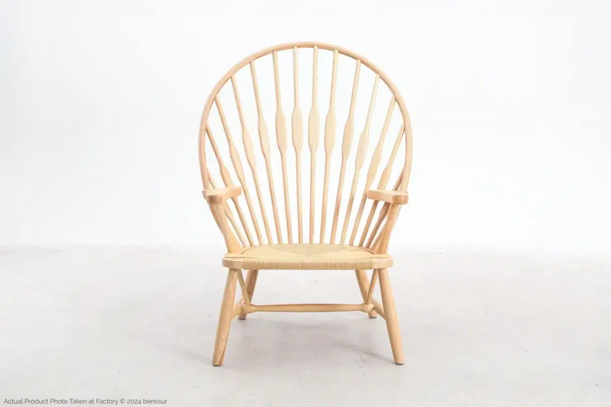 Hans Wegner_Peacock Chair_Replica_Paper Rope_Natural_Ash_Front A light wood Windsor-style chair with a rounded, high spindle back and woven seat, sitting on a plain, light-coloured floor against a white background.