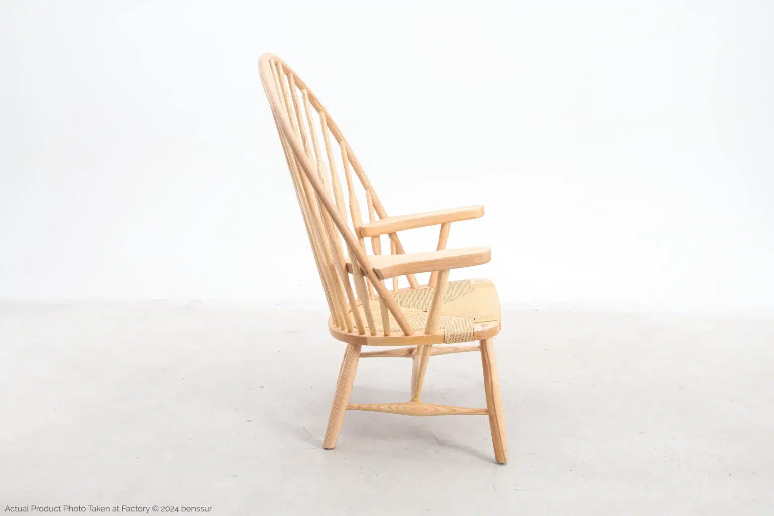 Hans Wegner_Peacock Chair_Replica_Paper Rope_Natural_Ash_Right Side view of a wooden armchair with a high, curved spindle back, woven seat, and angled legs, set against a plain white background.