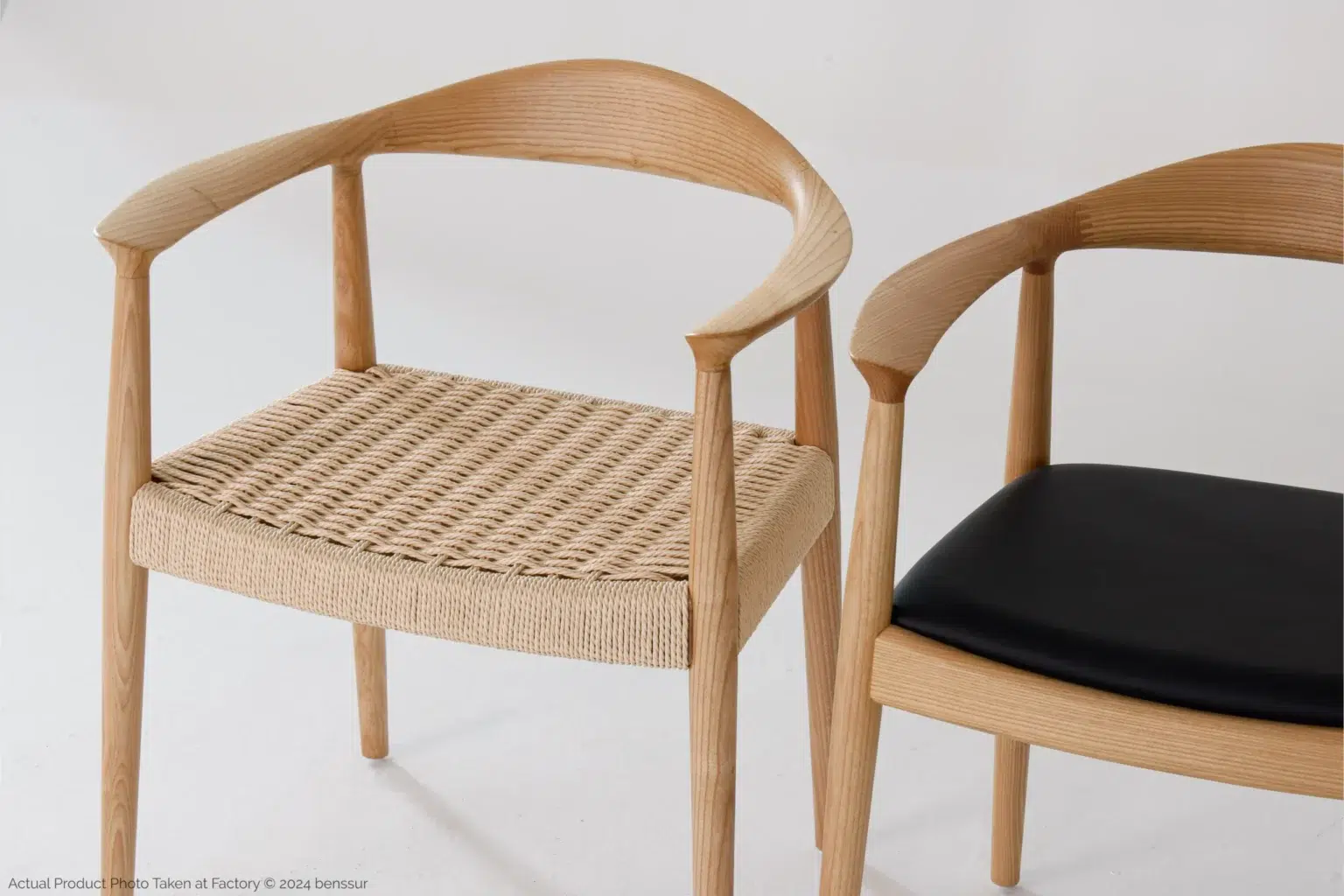 Hans Wegner_Round Chair_Replica_Microfiber_Natural_Ash_Detail_3 Two modern wooden chairs with curved backrests; one has a woven rattan seat, and the other has a smooth black cushioned seat, both against a plain white background.