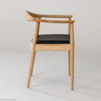 A modern wooden chair with a curved backrest and black cushioned seat, shown in profile against a plain white background. The design is minimalist with clean lines and light wood tones.