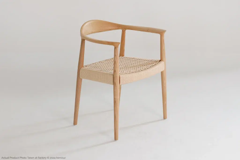 A modern wooden chair with a curved backrest and an open-weave cane seat, set against a plain white background.