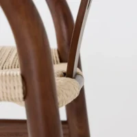 Close-up of a chair with smooth, curved wooden legs and a woven natural fibre seat, set against a plain white background.
