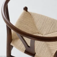 A close-up of a wooden chair with a curved backrest and a woven, light-coloured seat, photographed against a plain white background.
