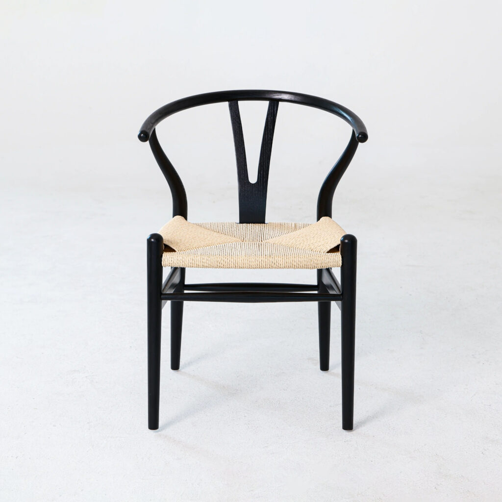A black wooden chair with a curved, wishbone-style backrest and a woven natural-coloured seat, photographed against a plain white background.