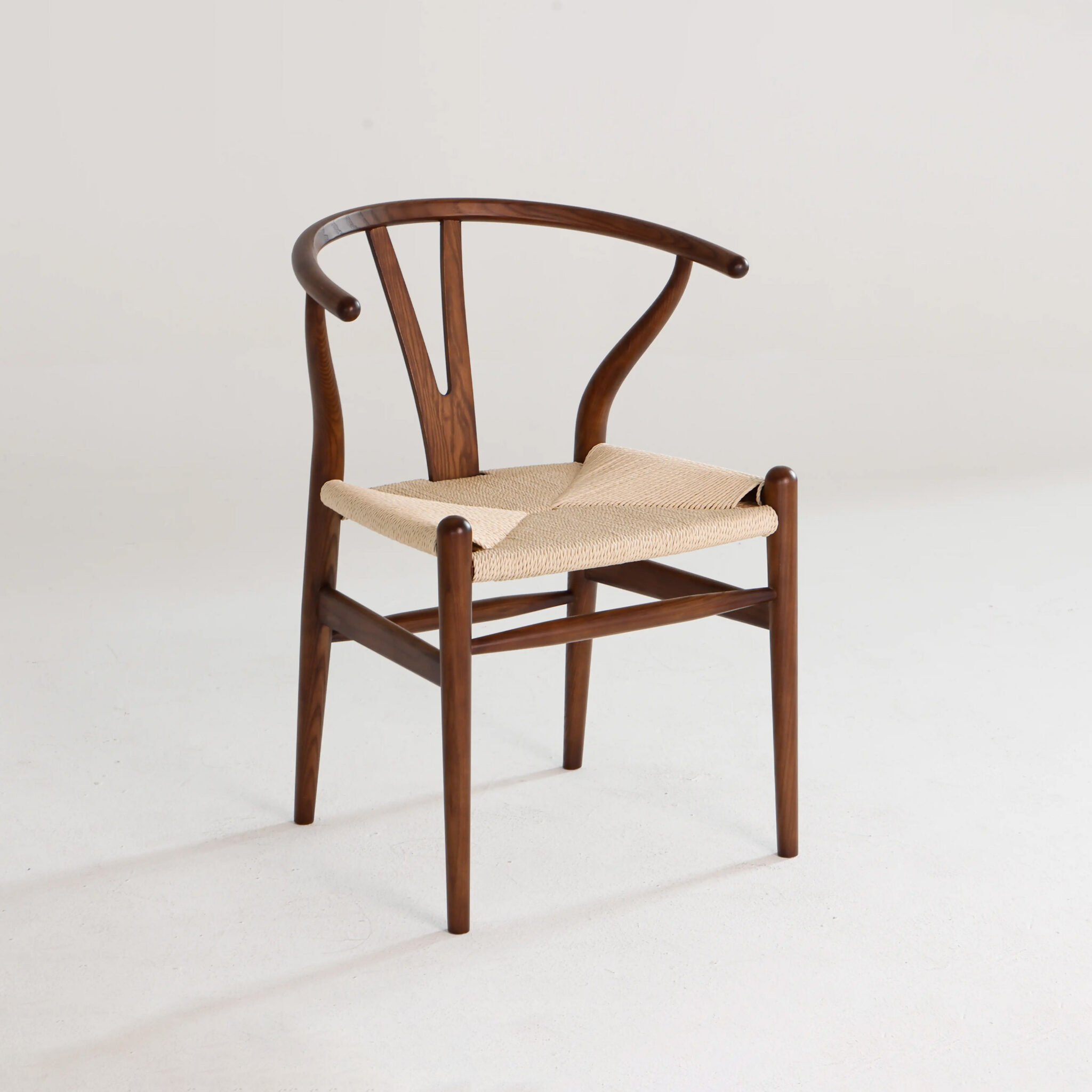 A wooden chair with a curved backrest and a woven seat, featuring sleek, minimalist design and angled legs, set against a plain light background.