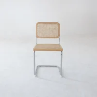 A single chair with a chrome frame and a woven cane seat and backrest sits on a plain white floor against a blank white background.