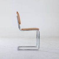 A side view of a modern chair with a chrome cantilever frame and tan leather seat and backrest, set against a plain white background.