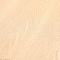 Light-coloured wooden surface with a smooth finish and visible wood grain patterns running diagonally across the image. The texture appears natural and clean, suitable for flooring or furniture.