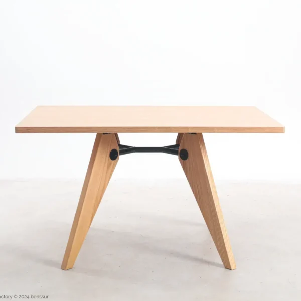 A minimalist wooden table with a rectangular top and two V-shaped legs connected by a black metal support bar, set against a plain white background.