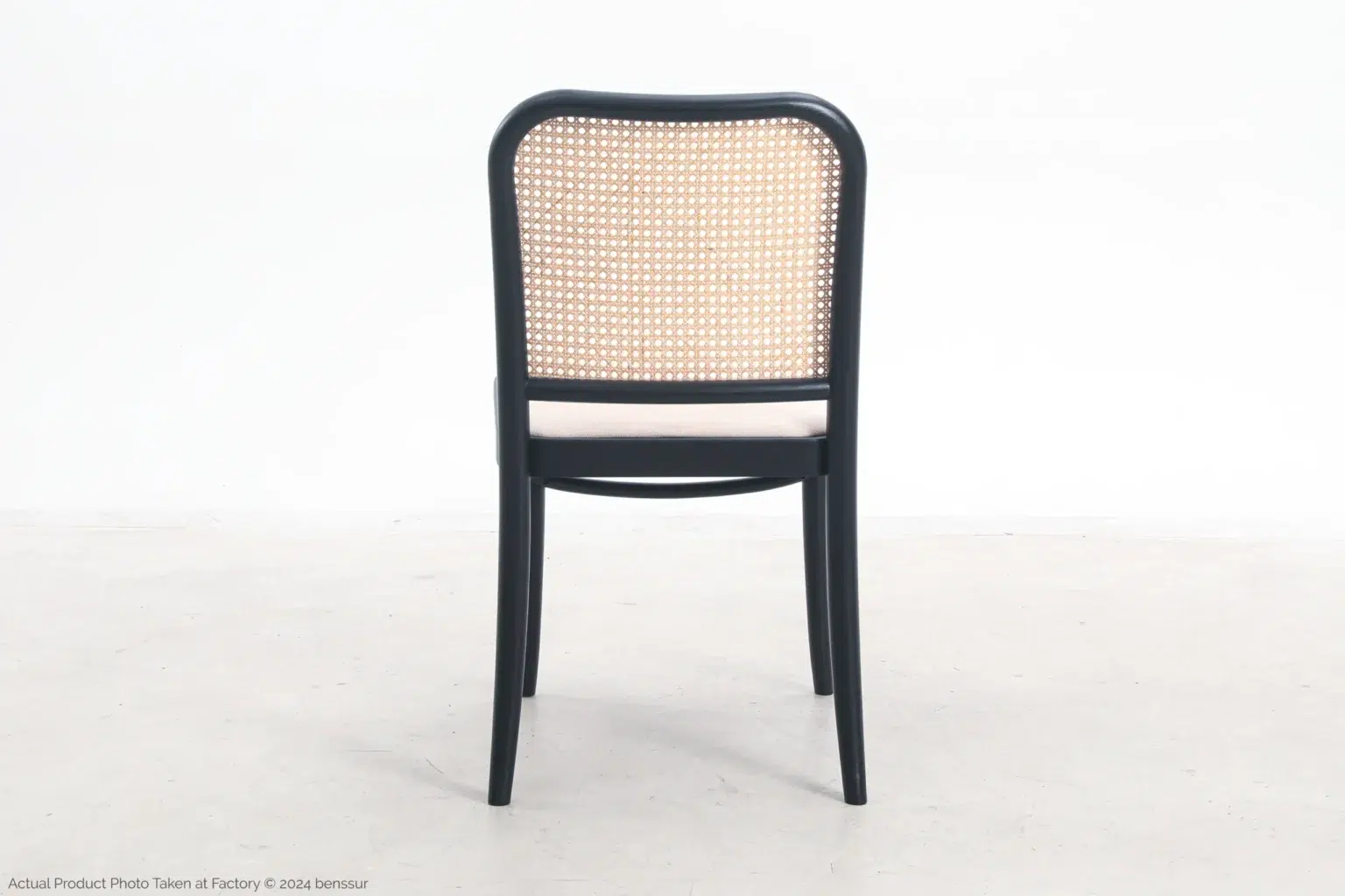 Josef Hoffmann_No811 Chair_Replica_Upholstered_Black_Ash_Back A black wooden chair with a woven cane backrest and a light-coloured cushioned seat, shown from the back against a plain white background.