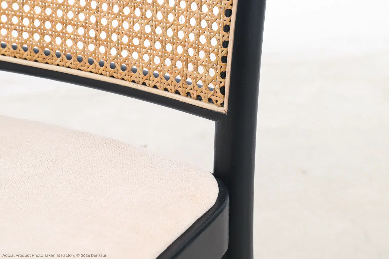Josef Hoffmann_No811 Chair_Replica_Upholstered_Black_Ash_Detail_3 Close-up of a chair with a beige woven cane backrest, black wooden frame, and a light-coloured upholstered seat against a plain, light background.