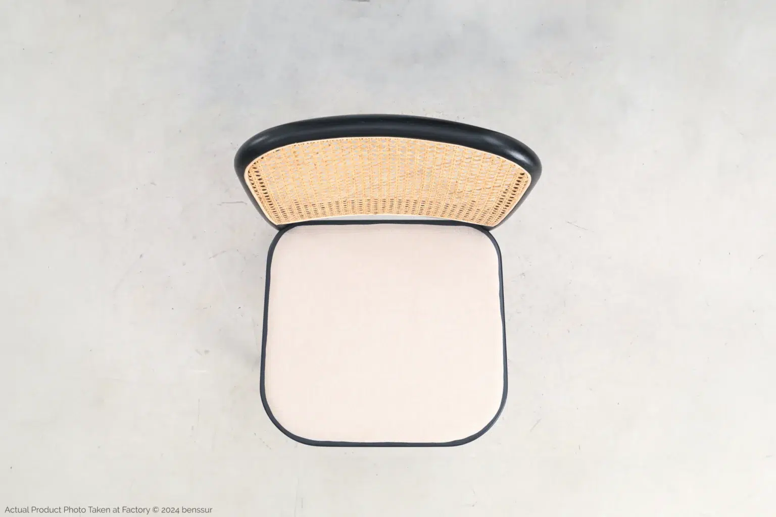 Josef Hoffmann_No811 Chair_Replica_Upholstered_Black_Ash_Top A top-down view of a chair with a light beige cushioned seat and a woven rattan backrest framed in black, placed on a light grey floor.