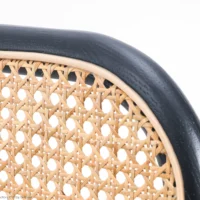 Close-up of a chair back with a black wooden frame and woven cane rattan in a natural light tan colour, showing detailed craftsmanship against a white background.