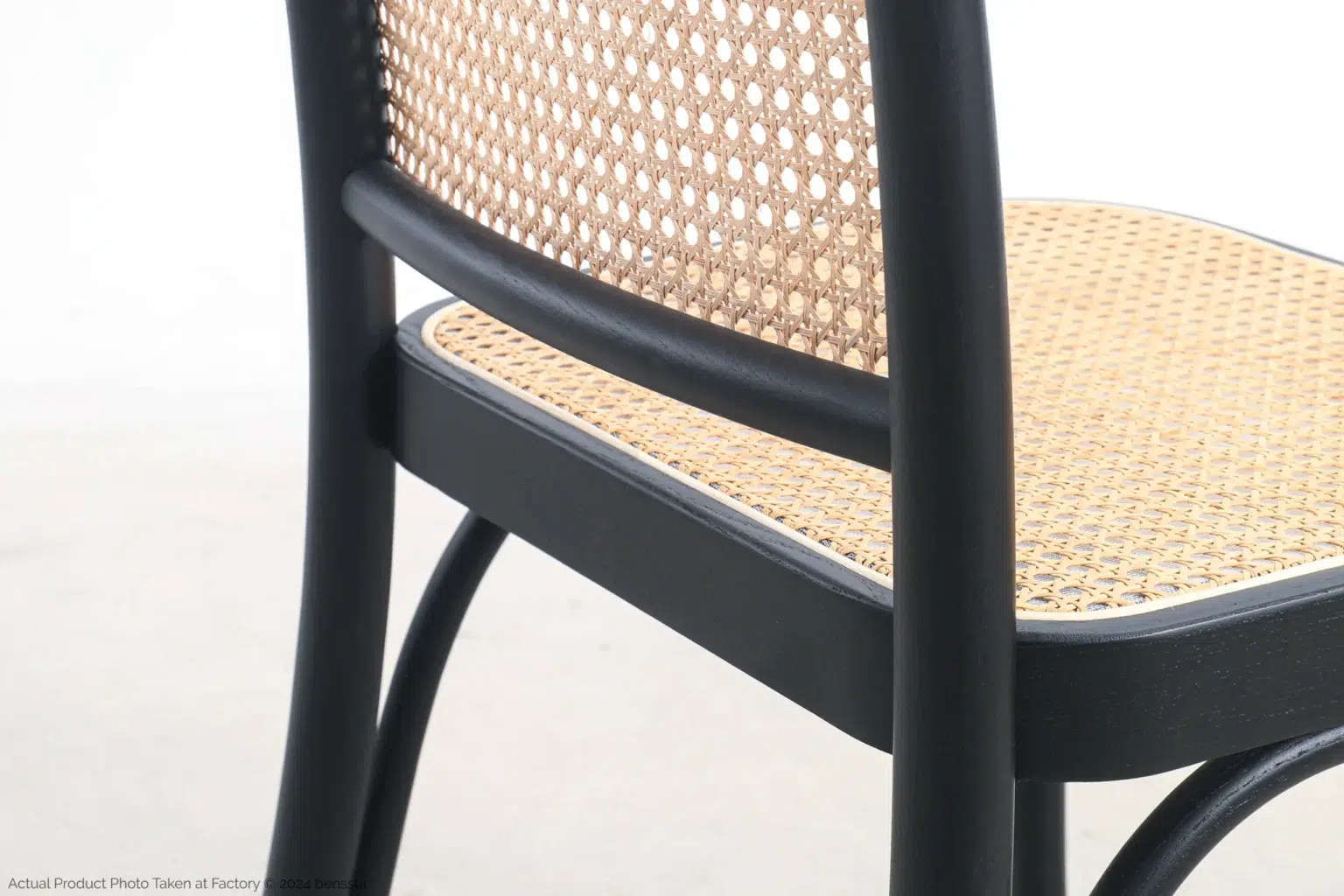 Josef Hoffmann_No811 Chair_Replica_Woven Caning_Black_Ash_Detail_3 Close-up of a chair featuring a black wooden frame with a woven rattan backrest and seat, set against a light background.