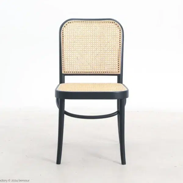 A black wooden chair with a woven cane seat and backrest, positioned on a light-coloured floor against a plain white background.