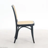 A side view of a chair with a black wooden frame and woven cane seat and backrest, placed on a light-coloured floor against a plain white background.