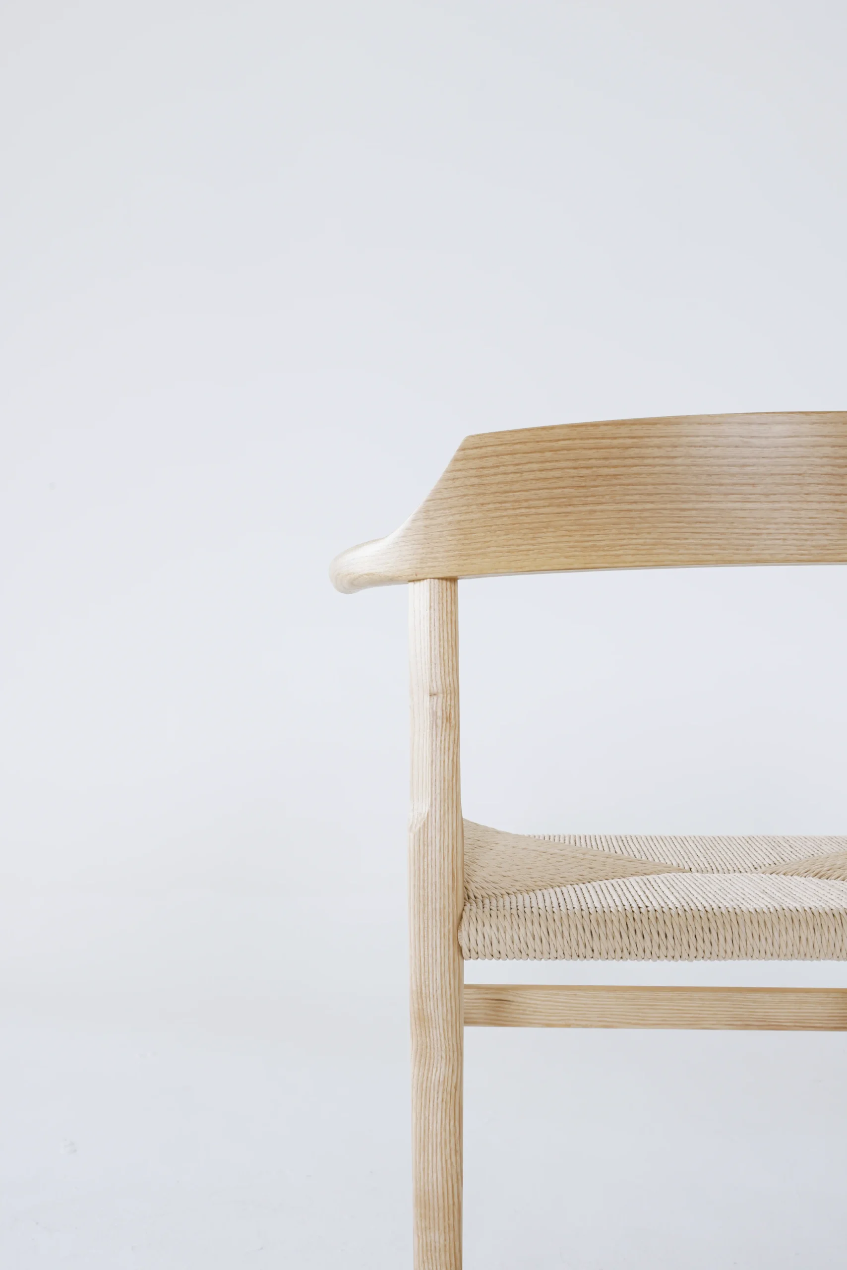 Detail of the backrest on Hans Wegner's Final Chair, highlighting the elegant European ash grain and smooth craftsmanship.