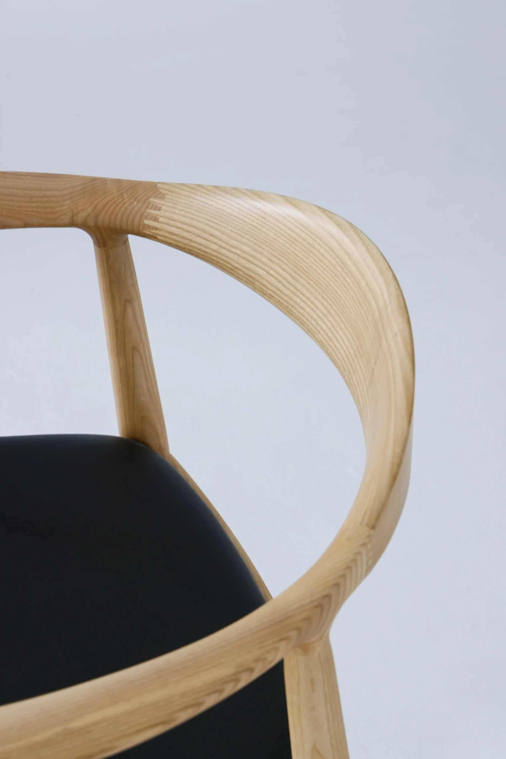 Detail of the backrest on Hans Wegner's Round Chair, highlighting the elegant European ash grain and smooth craftsmanship.