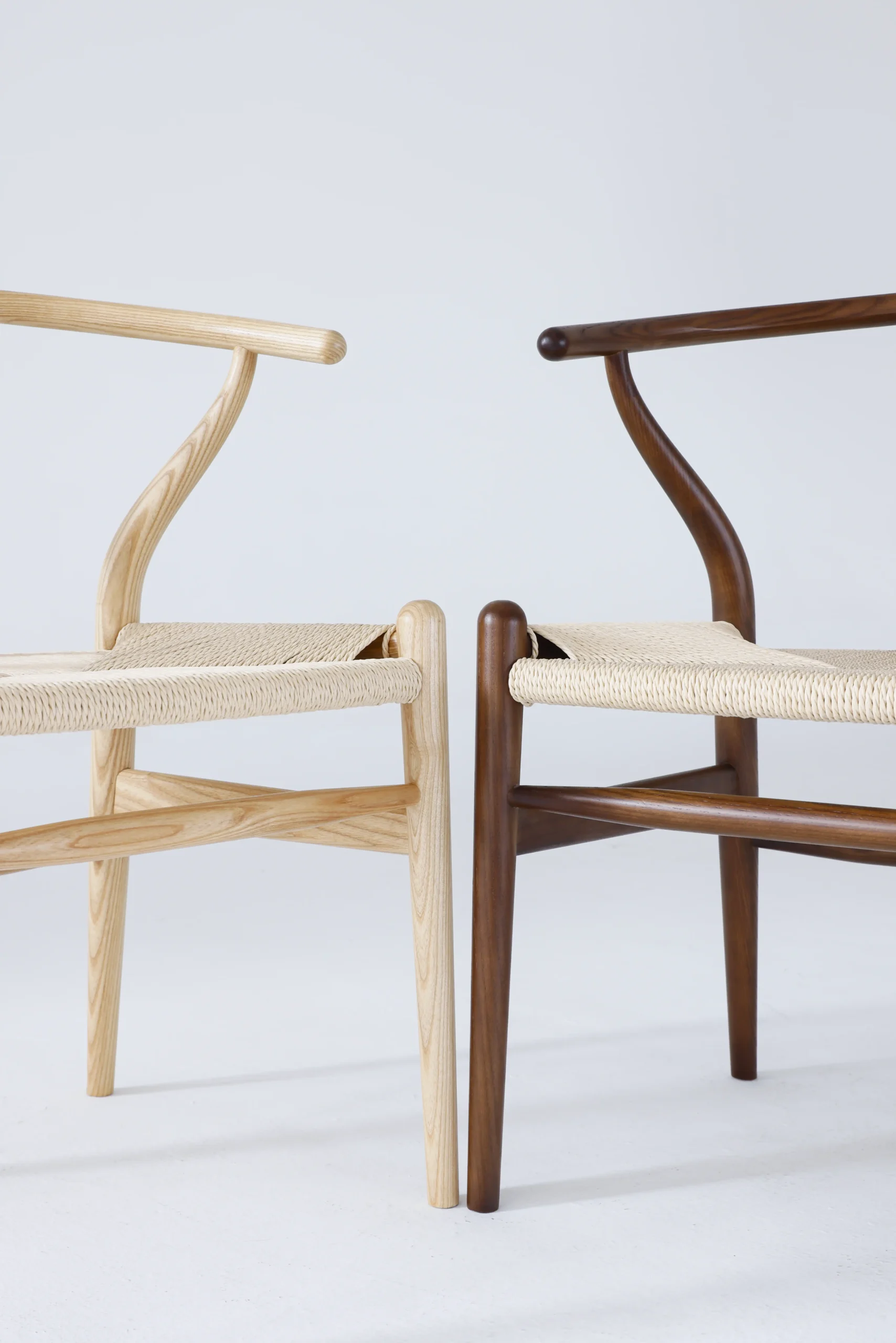 Two Hans Wegner Wishbone Chairs side by side, one natural and one brown, showcasing their iconic design.