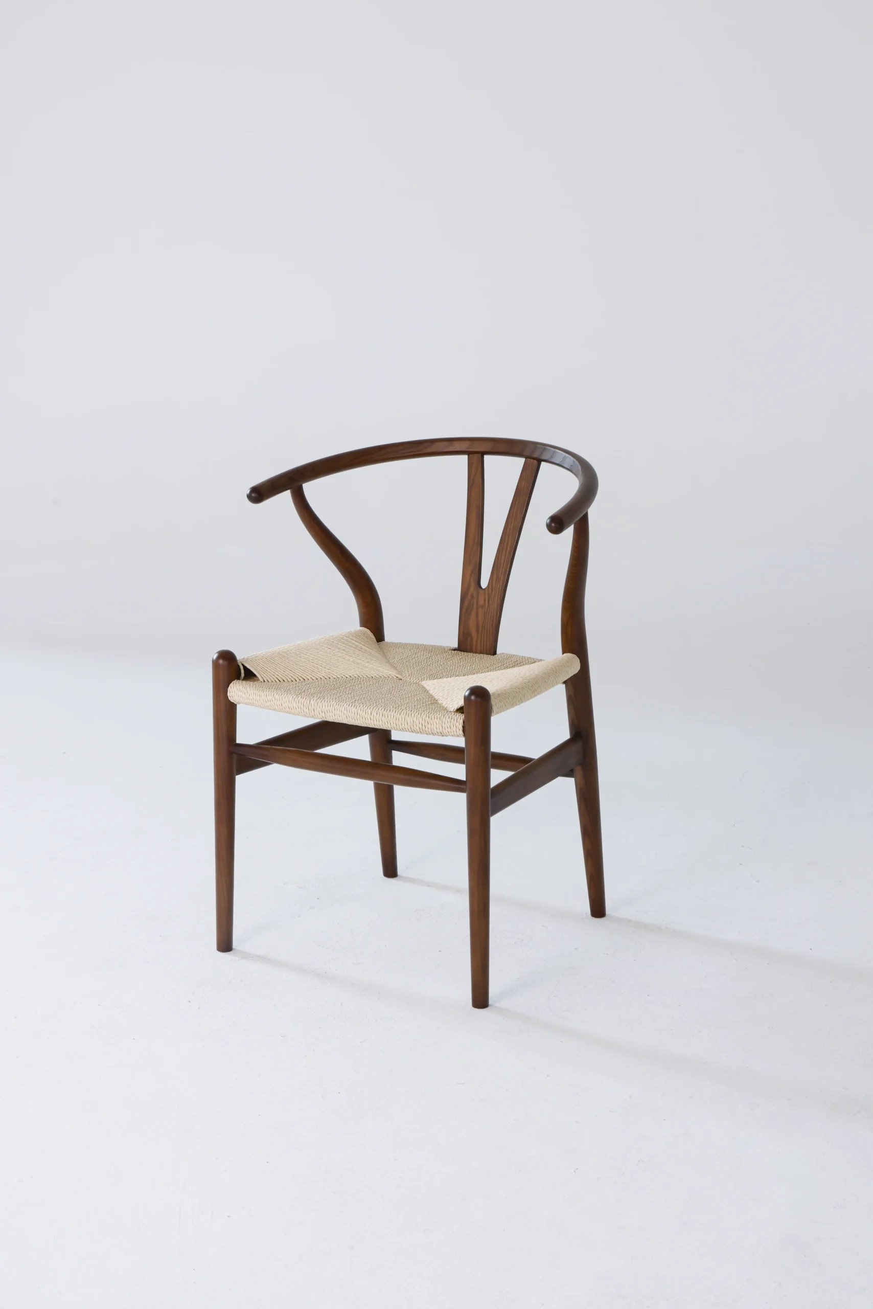 Photo of Hans Wegner's Wishbone Chair from a front-side angle, highlighting its distinctive Y-shaped backrest and woven seat, showcasing the chair's timeless design and craftsmanship.