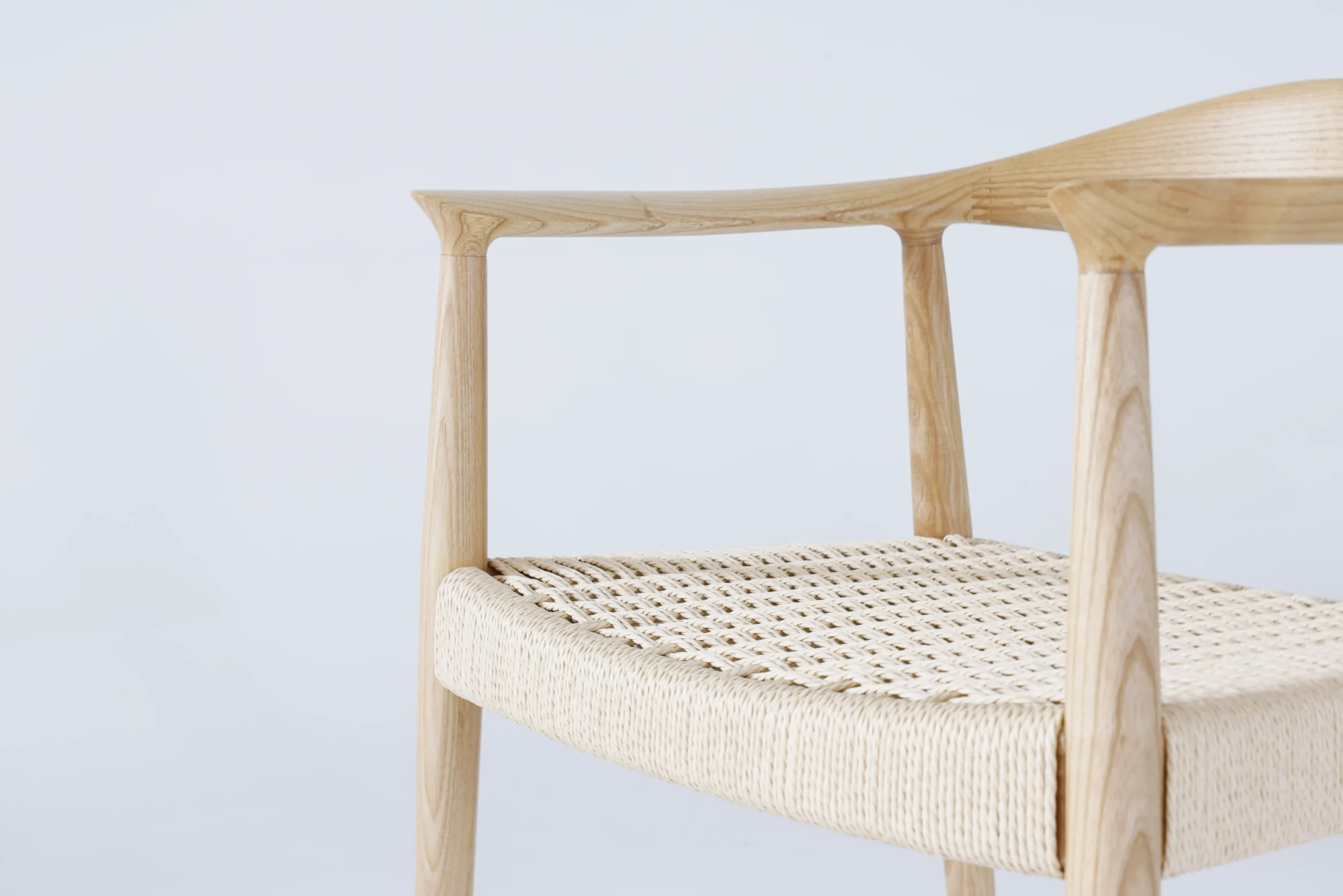 Photo of Hans Wegner's Round Chair with a paper rope seat, focusing on the intricate weave and craftsmanship of the seat, showcasing the natural texture and detailed workmanship in this classic design.