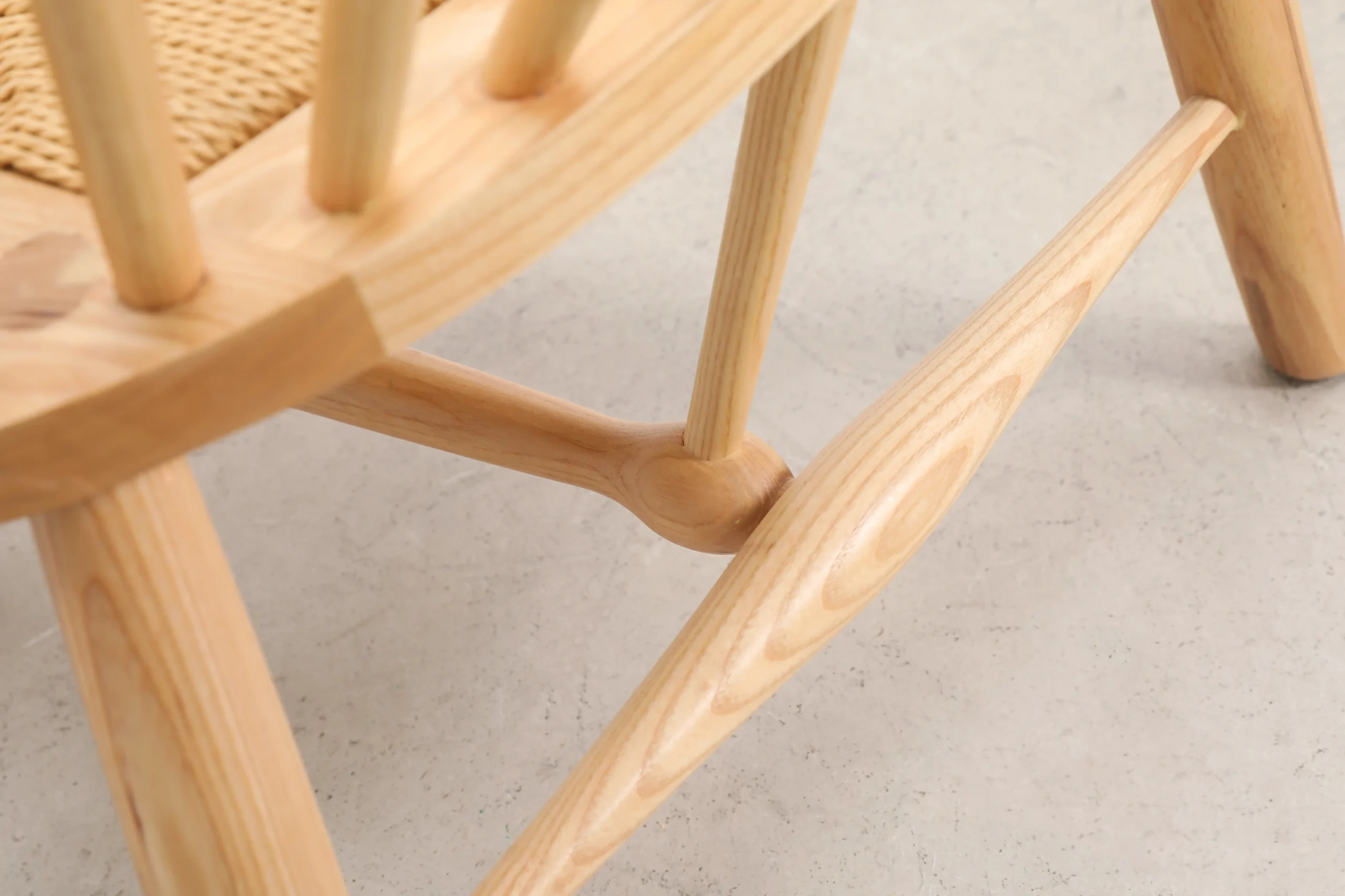 Photo of the lower detail in the back leg connection of Hans Wegner's Peacock Chair, highlighting the precise joinery and craftsmanship in the wooden frame, showcasing the chair's robust yet elegant design.