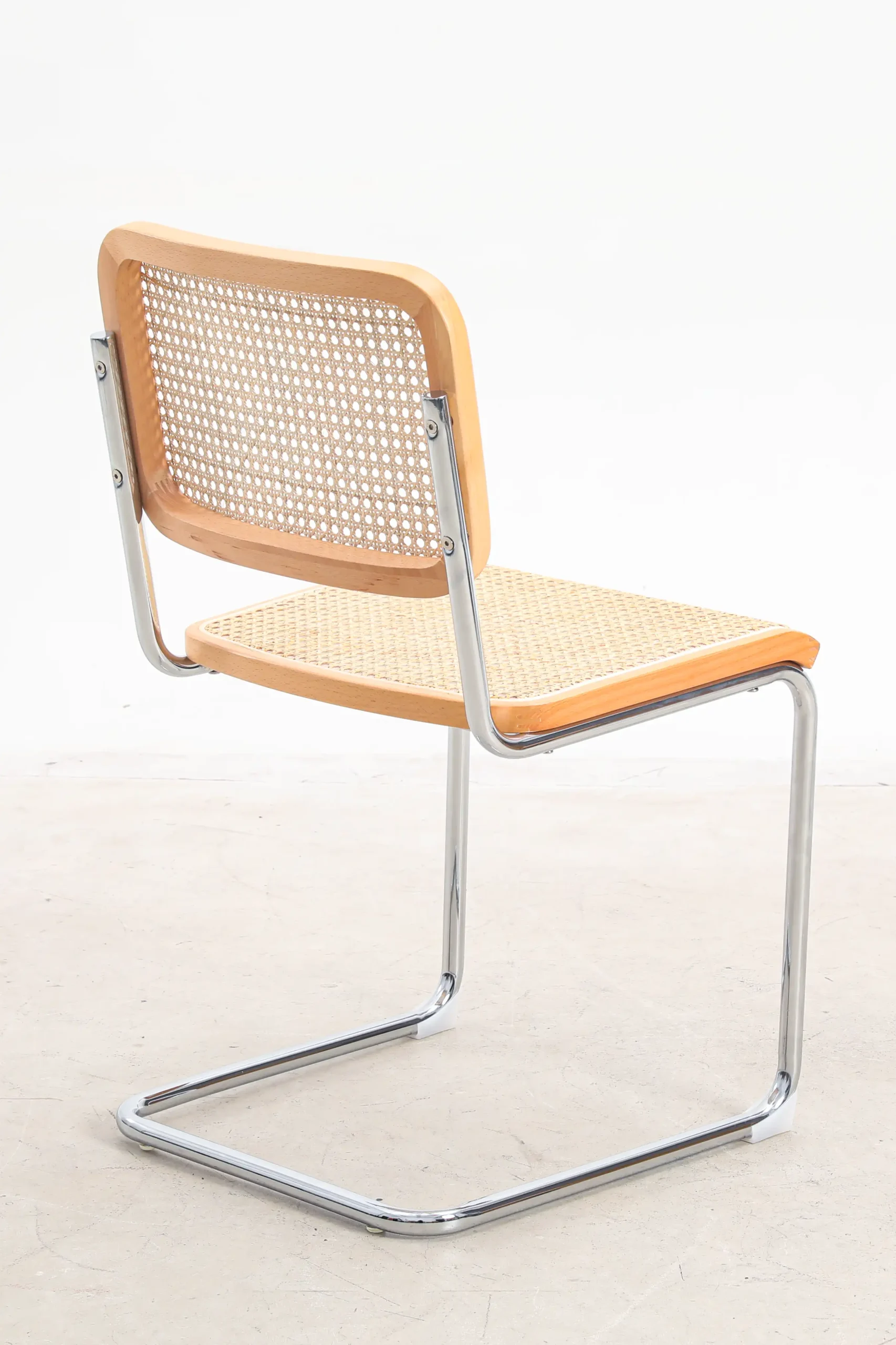 Photo of Marcel Breuer's B32 Cesca Chair from the back side, highlighting its iconic cantilevered frame and woven cane backrest, showcasing the blend of modernist design and craftsmanship.