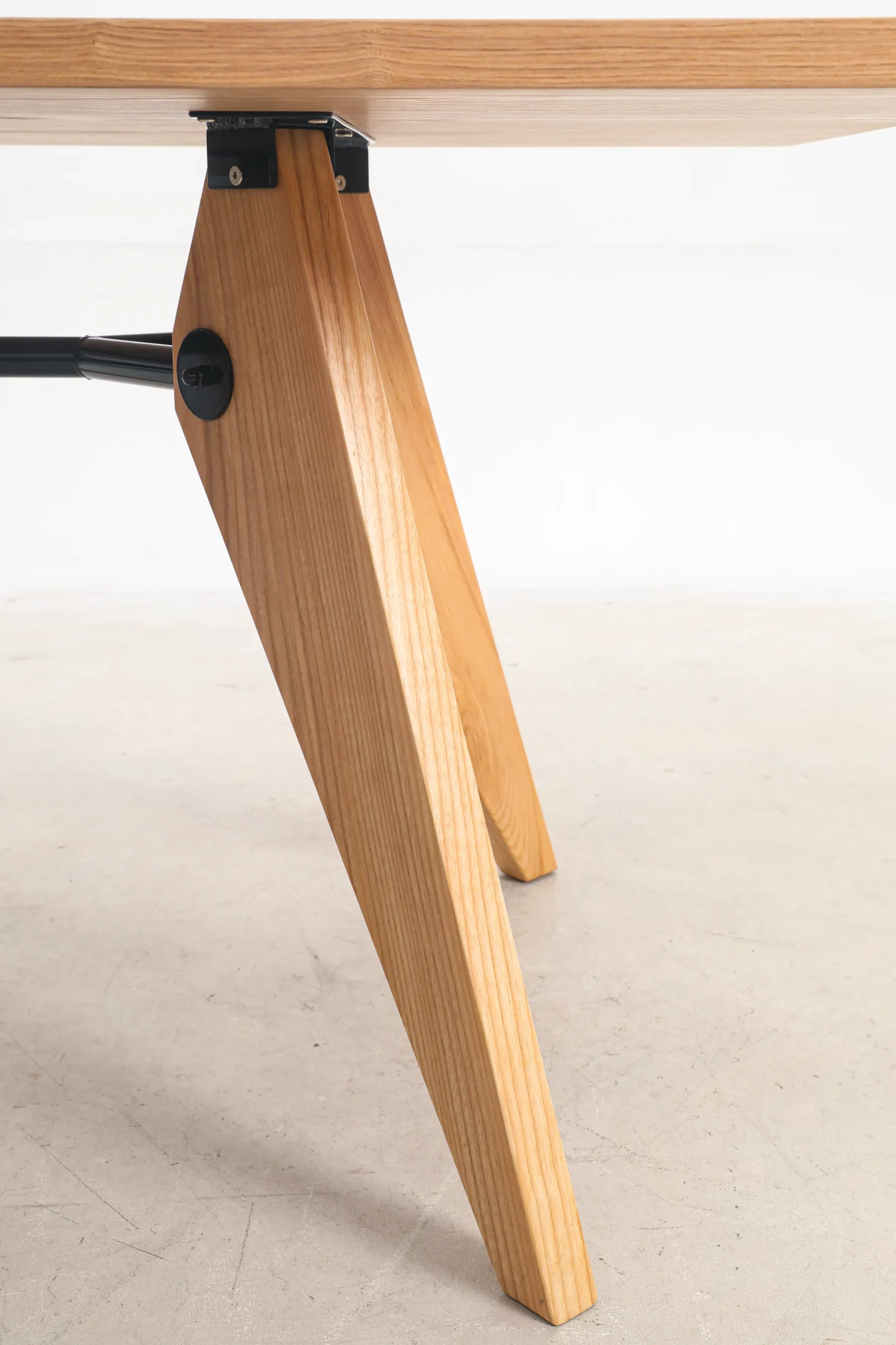 Photo of Jean Prouvé's S.A.M No.502 Table from a low angle, focusing on the structural details beneath the tabletop, showcasing the industrial design and robust metal framework characteristic of Prouvé's functionalist approach.