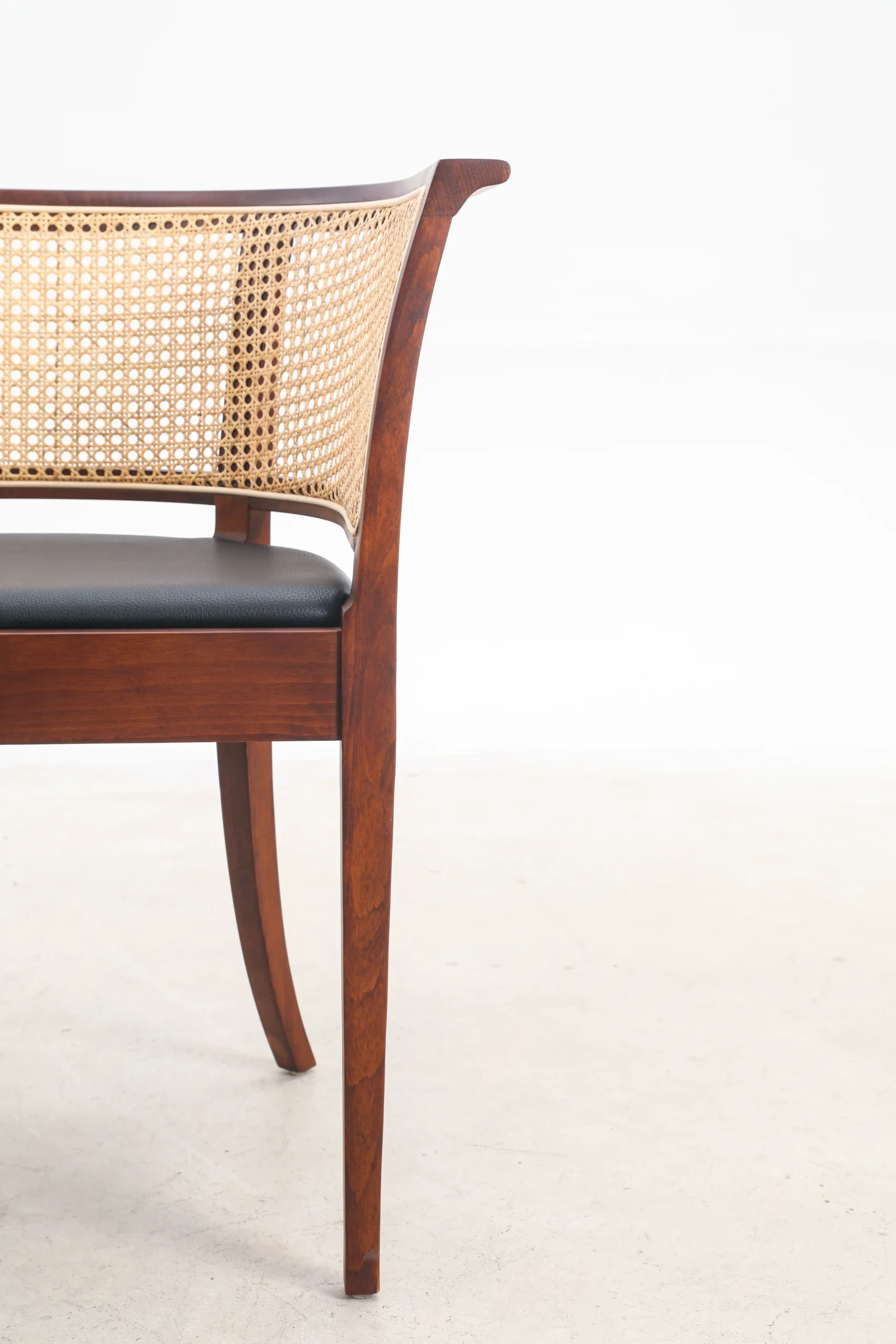 Photo of Kaare Klint's Faaborg chair, focusing on the front detail, showcasing its refined wooden frame and intricately woven cane seat, reflecting timeless craftsmanship and classic Danish design.